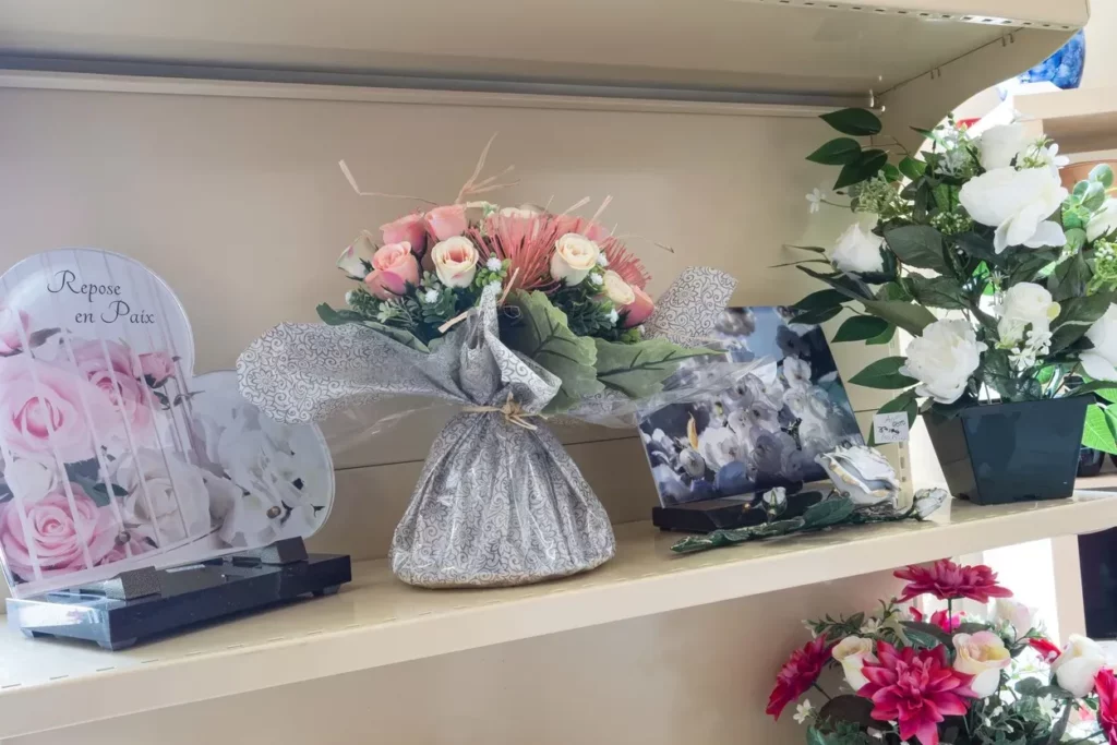 Sélection de bouquets de fleurs artificielles et plaques du souvenir en magasin.