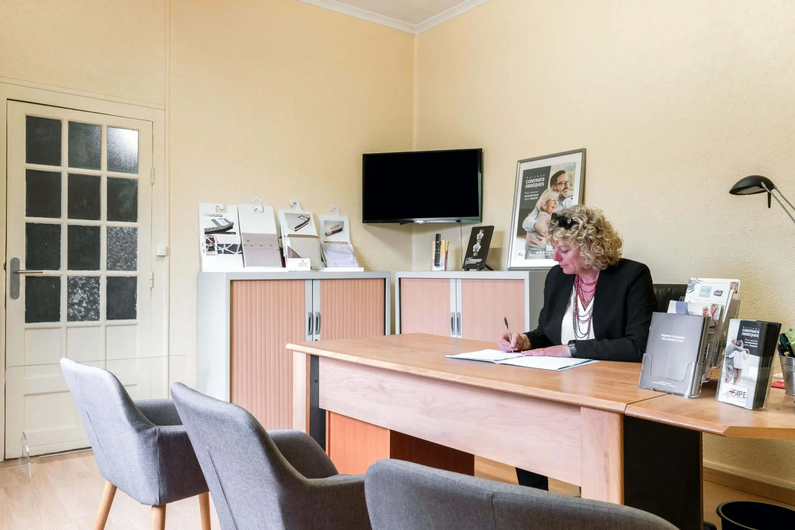 Conseillère funéraire rédigeant un document à son bureau de réception.