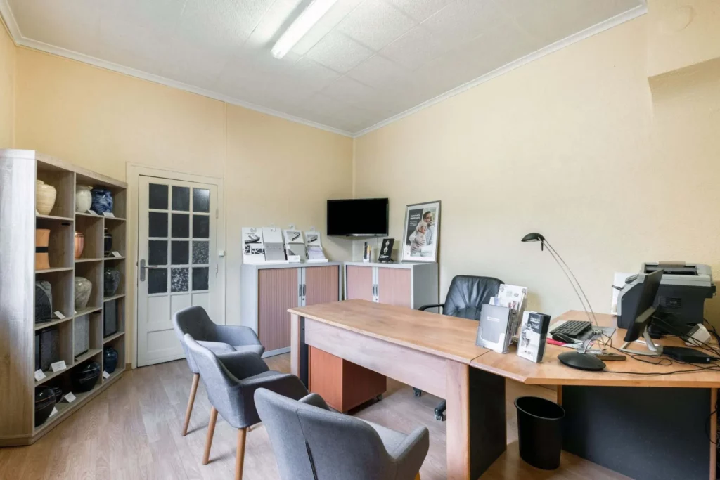 Bureau de réception funéraire avec sièges et exposition d'urnes.