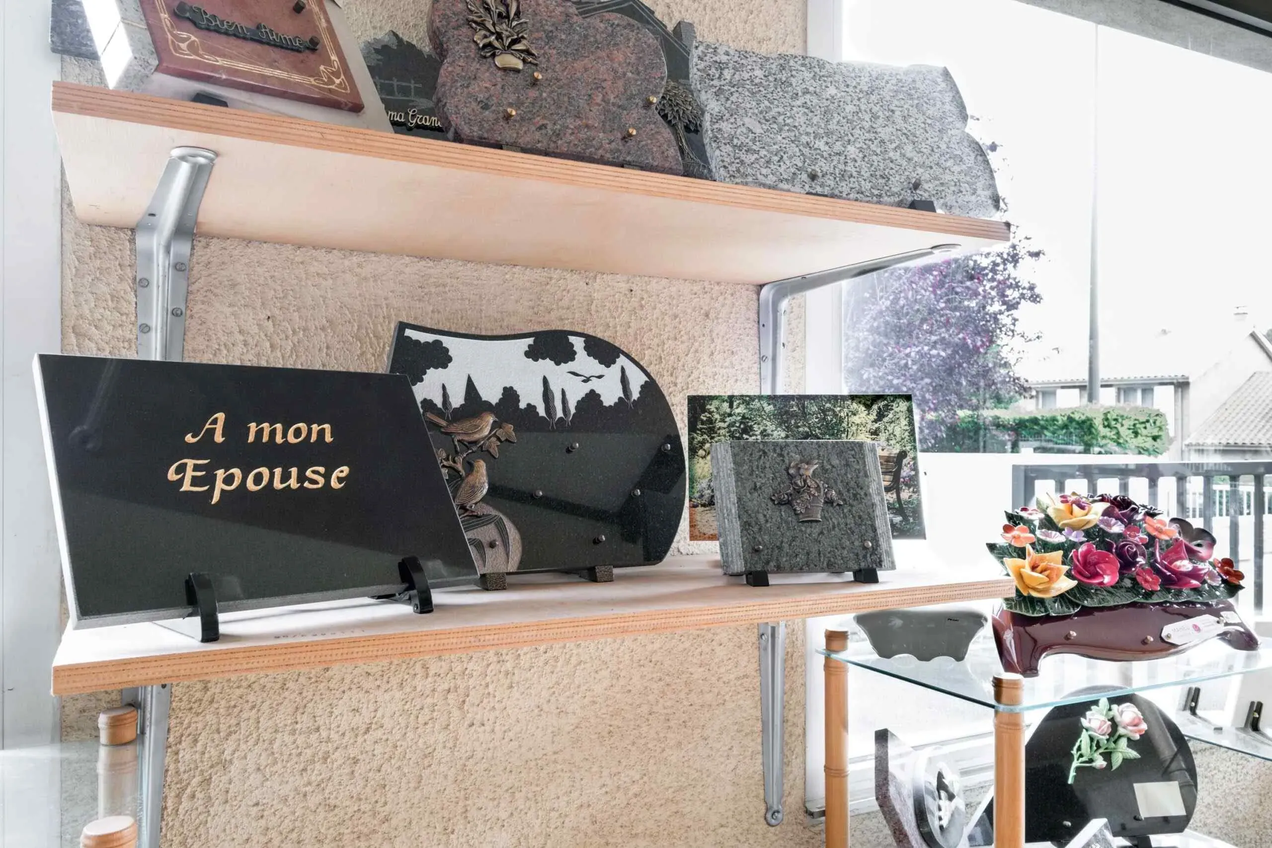 Étagères présentant diverses plaques funéraires personnalisées et ornements en céramique.